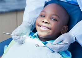 Child smiling during checkup with pediatric dentist