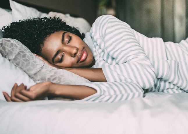 Woman in striped shirt sleeping peacefully in bed