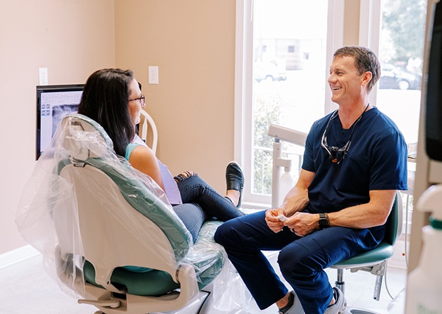 Man in dental chair smiling at dental team member