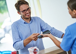 A man using a credit card to pay the cost of dental crowns