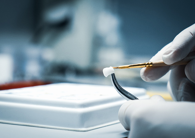 A lab worker processing a dental crown