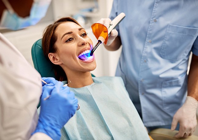 Dentist applying UV light to patient’s filling