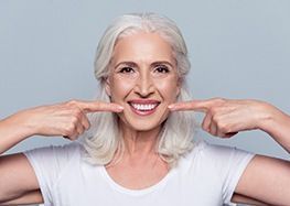 senior woman pointing to her smile 