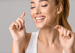 Woman performing dental implant care in Rome by flossing