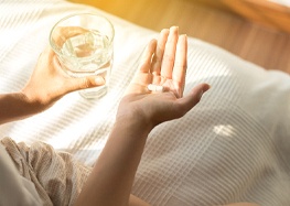 Woman taking painkillers after receiving dental implants in Rome