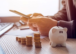 a person budgeting and a piggy bank sitting on a desk