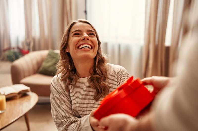 A smiling woman receiving a Valentine’s Day gift