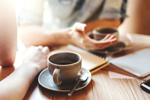 Cups of coffee on desk between two people talking